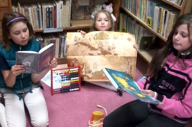 dzieci czytają książki w bibliotece