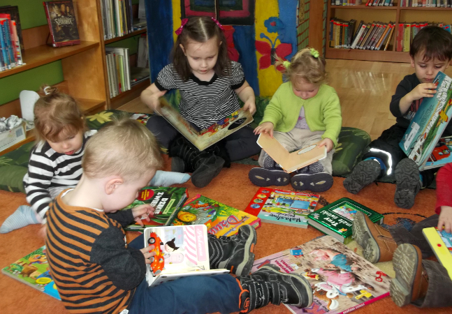 dzieci czytają książki w bibliotece