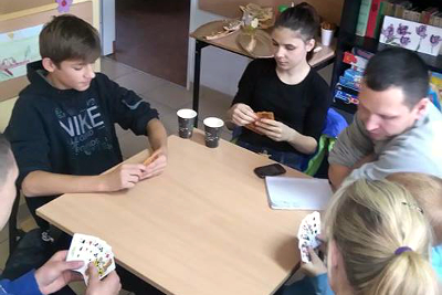 mlodzież gra w karty przy stole