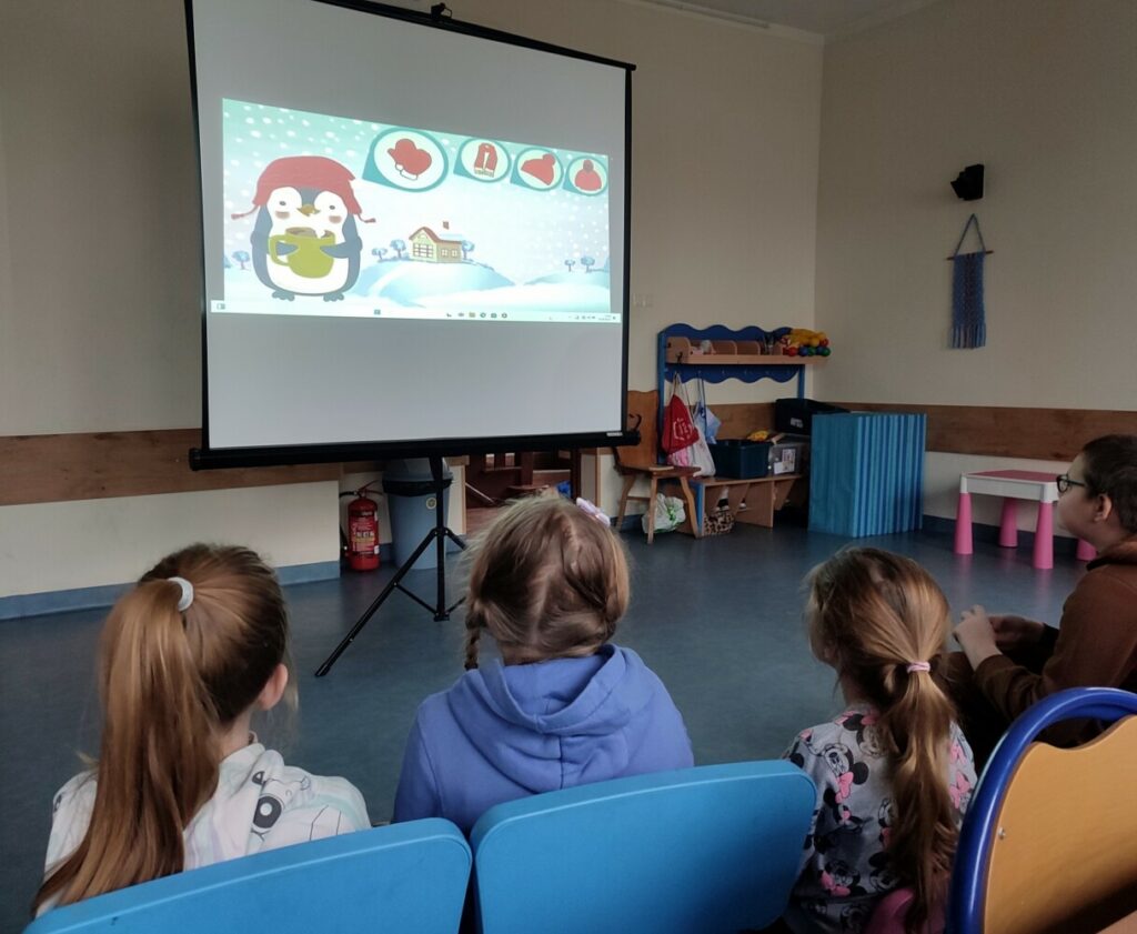 Fotografia przedstawia dzieci oglądające filmik o bezpiecznych feriach.